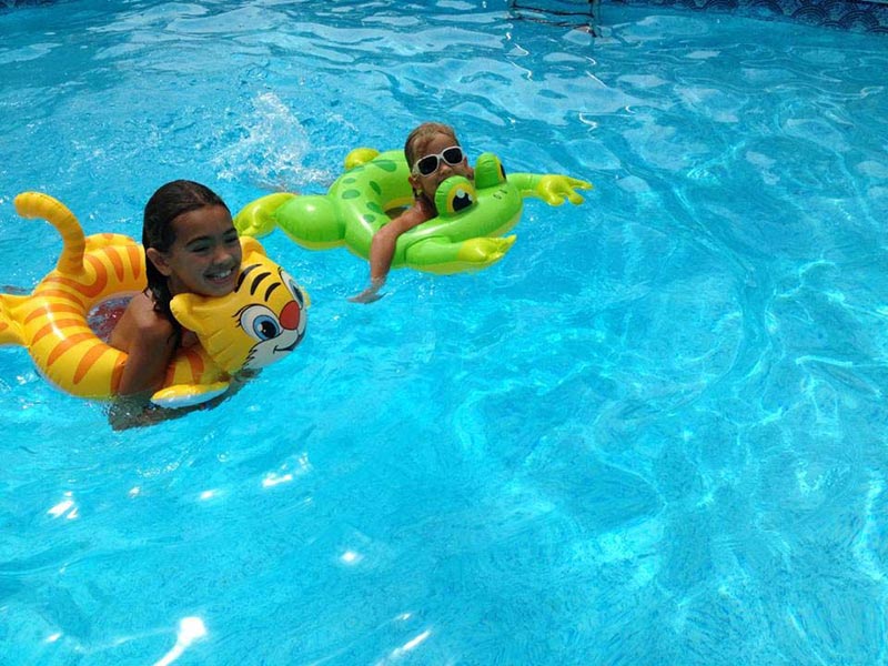 two kids on floaties in pool